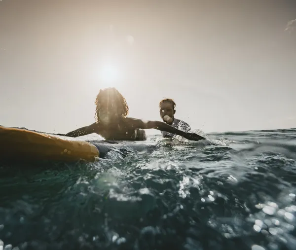 Two surfers paddling at sunset