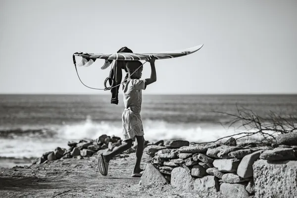 Boy running with surfboard overhead (black & white)